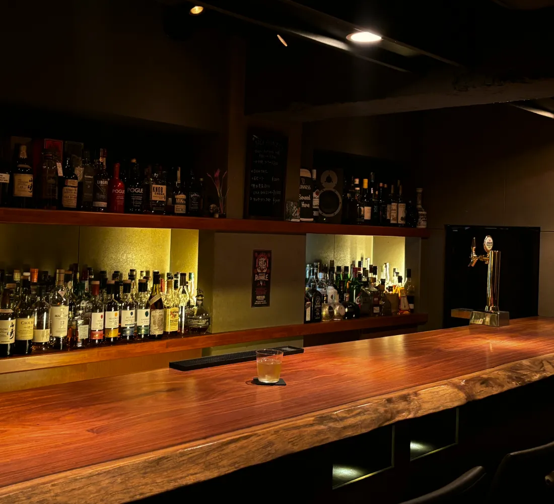 バーのカウンター席と棚に並ぶボトル