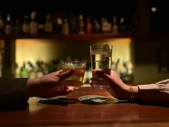 バーカウンターで乾杯する2人